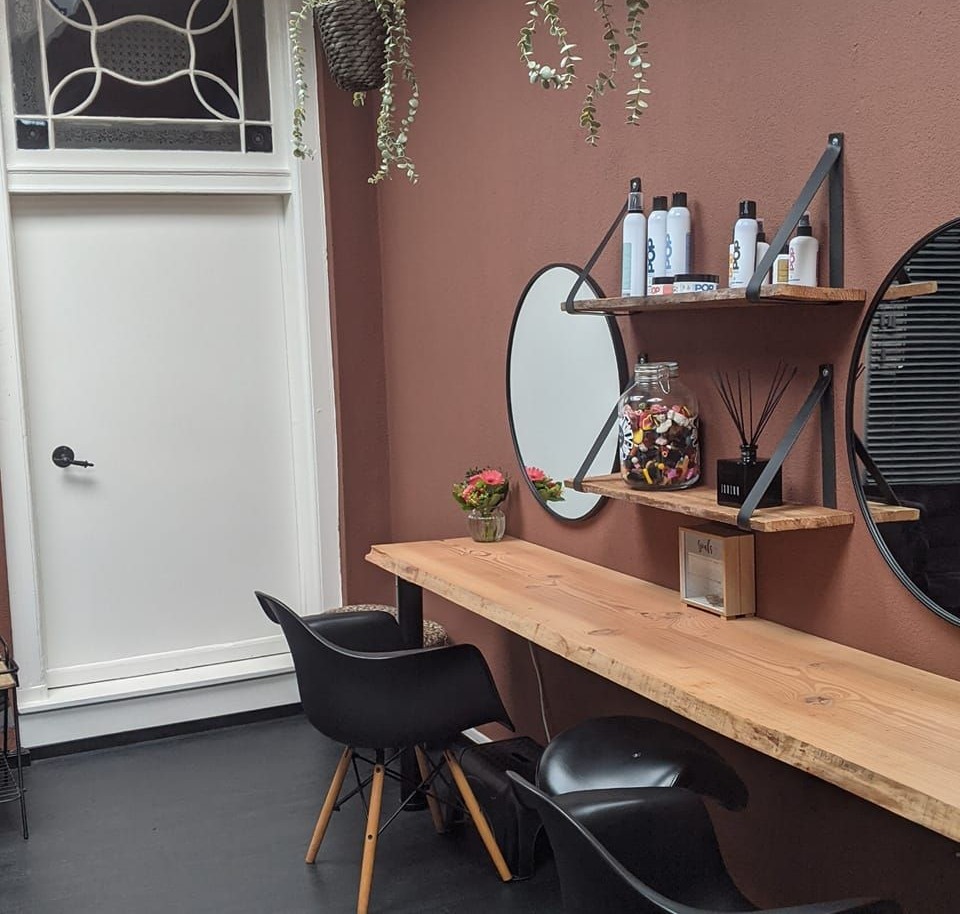 De werkplek in de salon: houten blad, ronde spiegels en de oude deur met glas-in-lood erboven