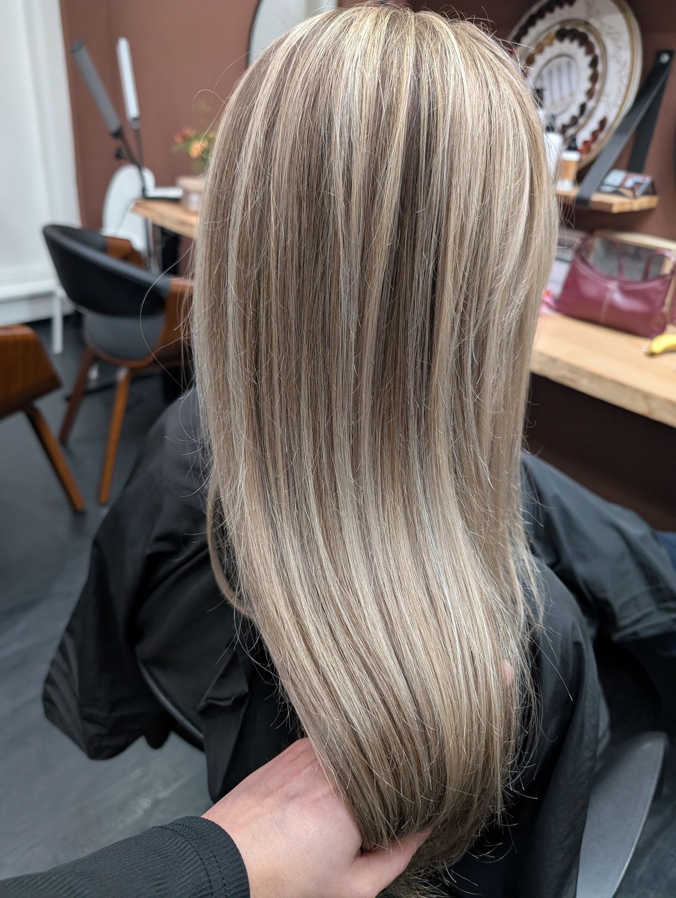 Lang asblond haar met highlights, in de hand van de kapster